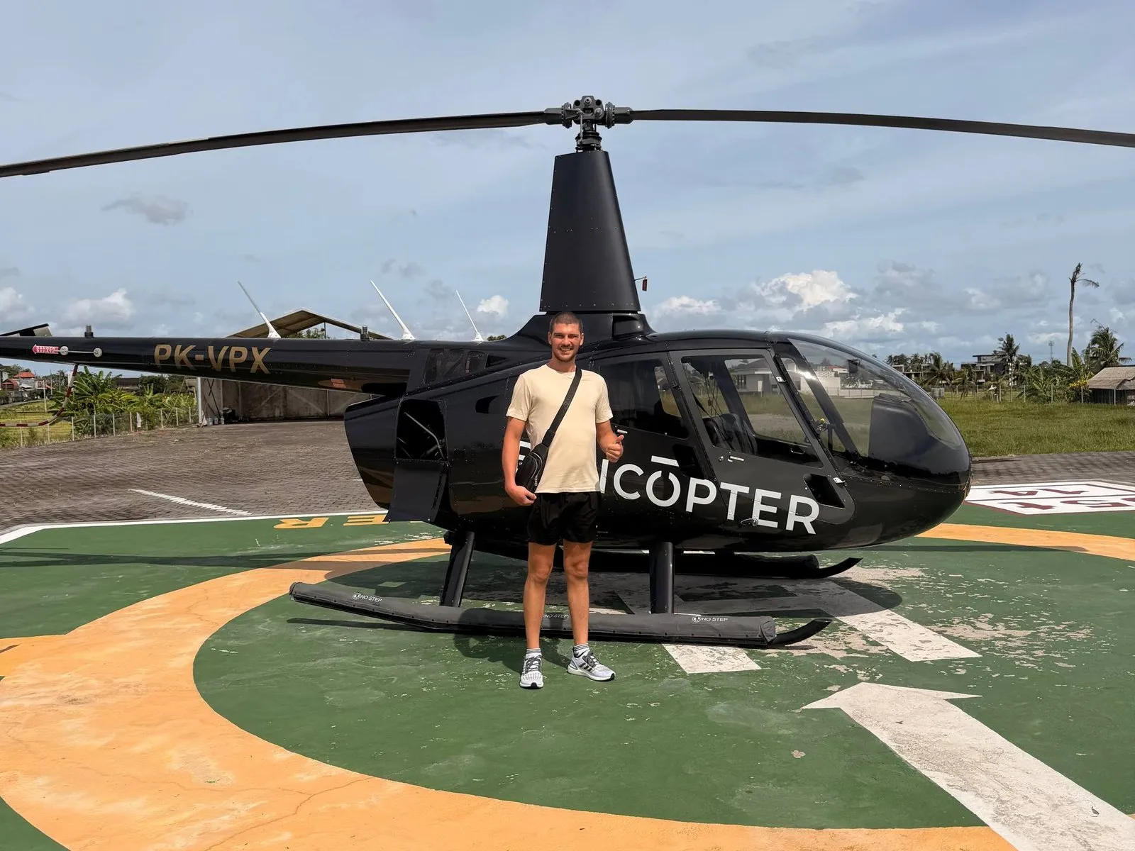 Marco standing in front of a helicopter on a helipad in Bali.