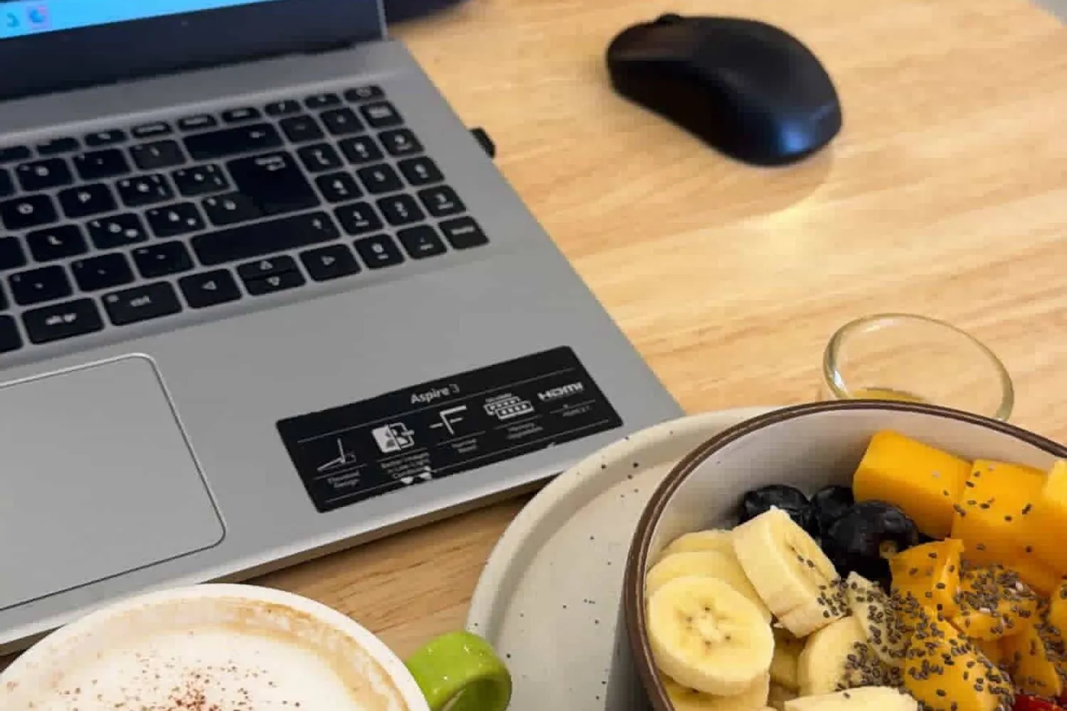 Laptop with code, a cappuccino, and a fruit bowl at a cafe in Ao Nang, Thailand.
