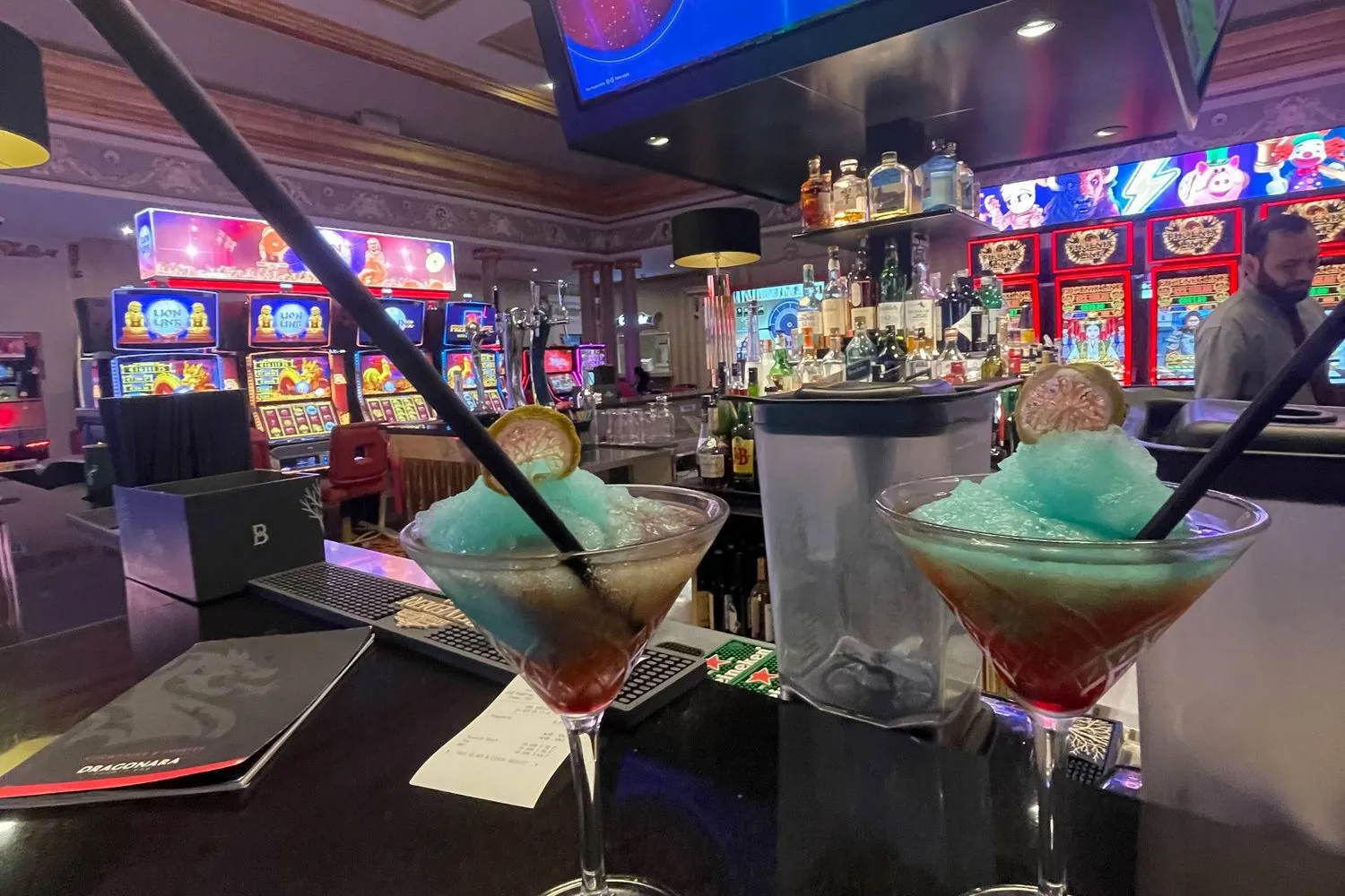 Cocktails on a casino bar with slot machines and a bartender behind, in Malta.