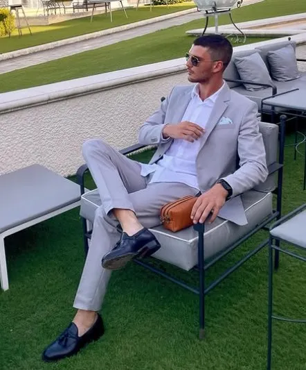 Marco Nicola Messina in a light grey suit, seated on an outdoor terrace.
